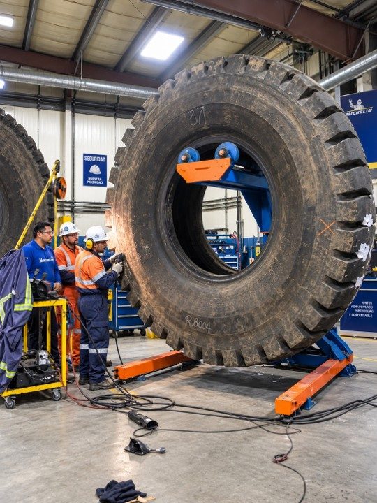 Equipo de mantenimiento montando un neumático gigante en el taller